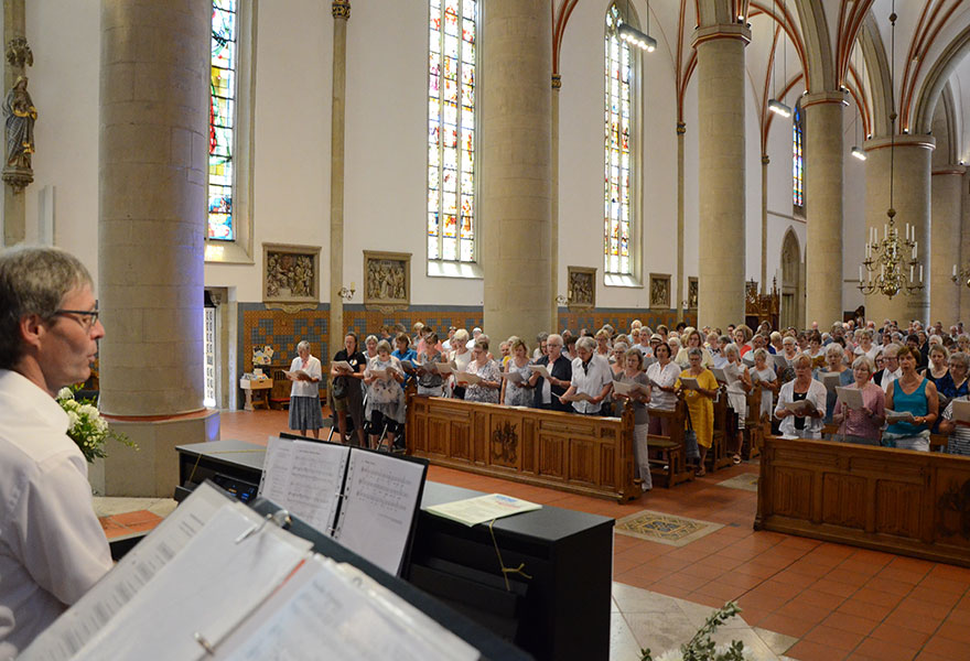 Thomas Kleinen dirigiert die Sängerinnen und Sänger in der Kirche.