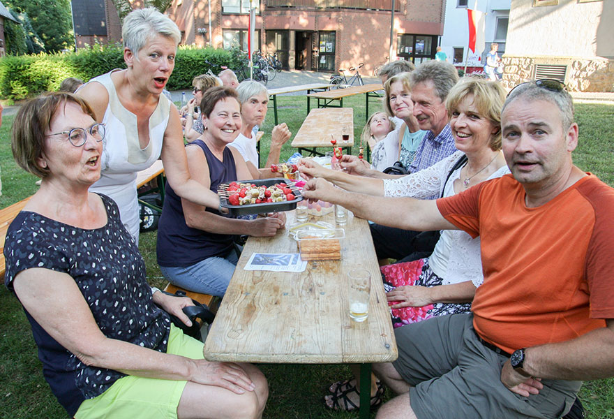 Menschen sitzen an einem langen Tisch und lachen in die Kamera. Menschen sitzen an einem langen Tisch und lachen in die Kamera.