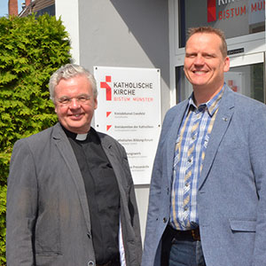 Kreisdechant Johannes Arntz und Benedikt Helmich stehen nebeneinander und lächeln in die Kamera. Kreisdechant Johannes Arntz und Benedikt Helmich stehen nebeneinander und lächeln in die Kamera.