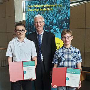 Luke Hedtfeld, Schulleiter Thomas Birkenhauer und Mika Wolff (von links) stehen vor einem Banner.