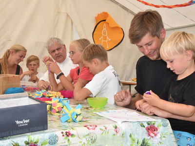 Mareike und Jan Kamping und Weihbischof Reinhard Hauke basteln im Kirchenzelt auf dem Campingplatz in Tossens mit Kindern.