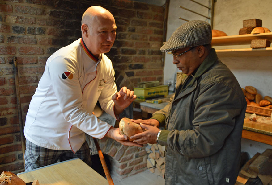 Bäckermeister Jörg Terjung zeigt einem indischen Gast ein Brot, das gerade aus dem Ofen kommt.