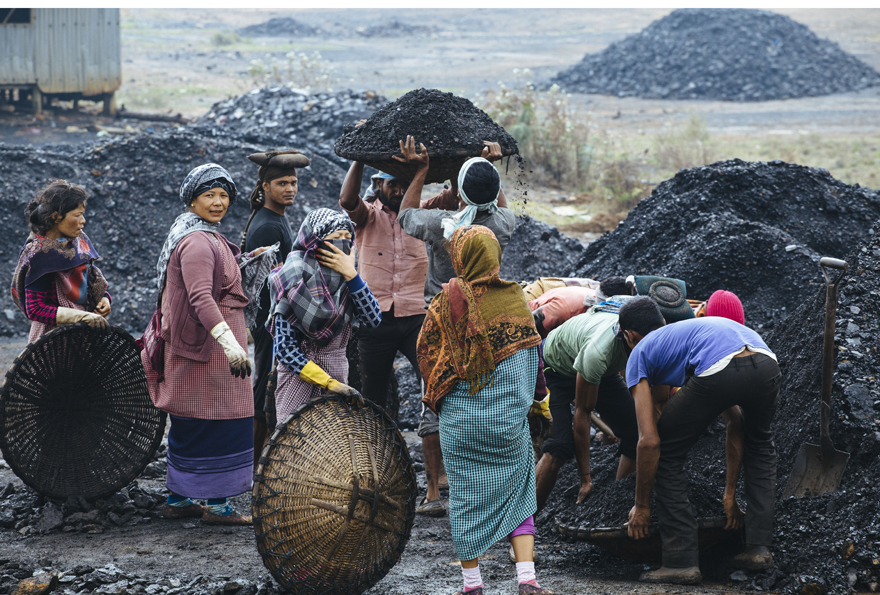 Indische Frauen und Männer laden Kohle in Transportkörbe.