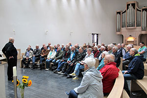 Die Erwachsenenmessdiener hören in der Kirche dem Gästeführer zu.