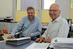 Josef Vossel und Norbert Mertens sitzen nebeneinander am Schreibtisch. Josef Vossel und Norbert Mertens sitzen nebeneinander am Schreibtisch.