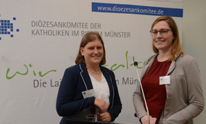 Lisa-Marie Singer (links) und Kerstin Stegemann stehen vor einer weißen Wand mit dem Logo des Diözesankomitees.