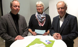 Hinter einem runden weißen Stehtisch, auf dem papiere liegen, stehen (von links) Ansgar Wucherpfennig, Andrea Tafferner und Peter Berker (KatHO). 