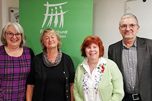 Beate Koritko, Christina Hoogland, Eva Feld und Heinz Kues stehen nebeneinander vor dem Logo des Verbandes.