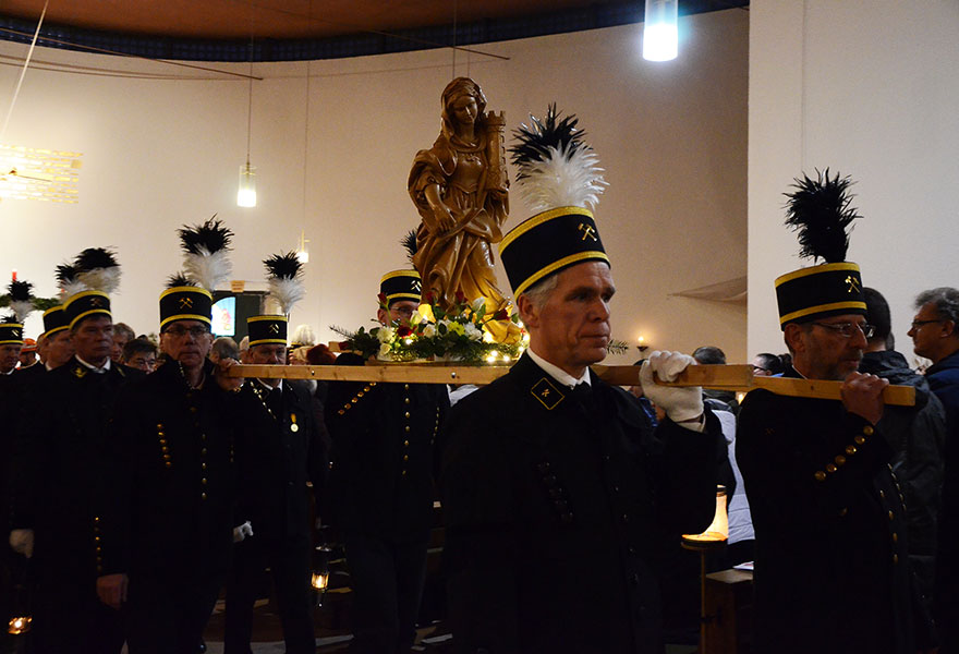 Männer in Bergbauuniform tragen die Figur der heiligen Barbara.
