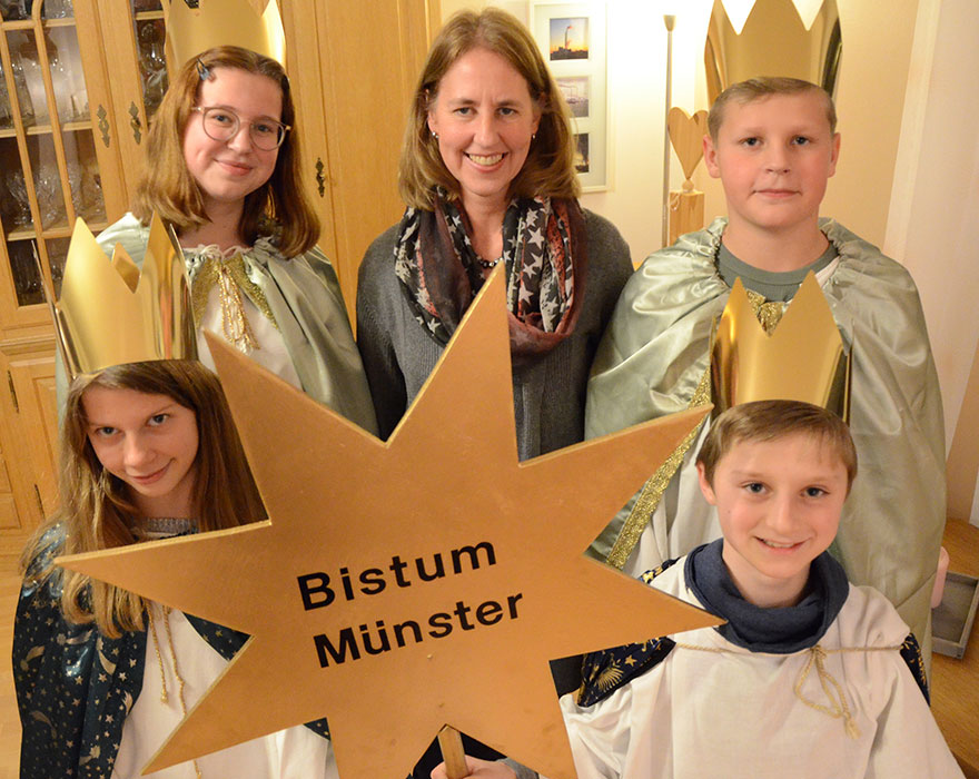 Die Sternsinger aus Horneburg haben ihre Gewänder angezogen und einen goldenen Stern mit dem Aufdruck "Bistum Münster" in der Hand.