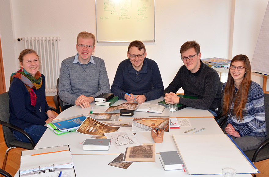 Teilnehmer des Sprachenjahrs sitzen im Halbkreis am Tisch.