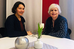 Irmgard Neuß (rechts) und Rendel Werthmöller sitzen an einem Tisch und lächeln in die Kamera. 