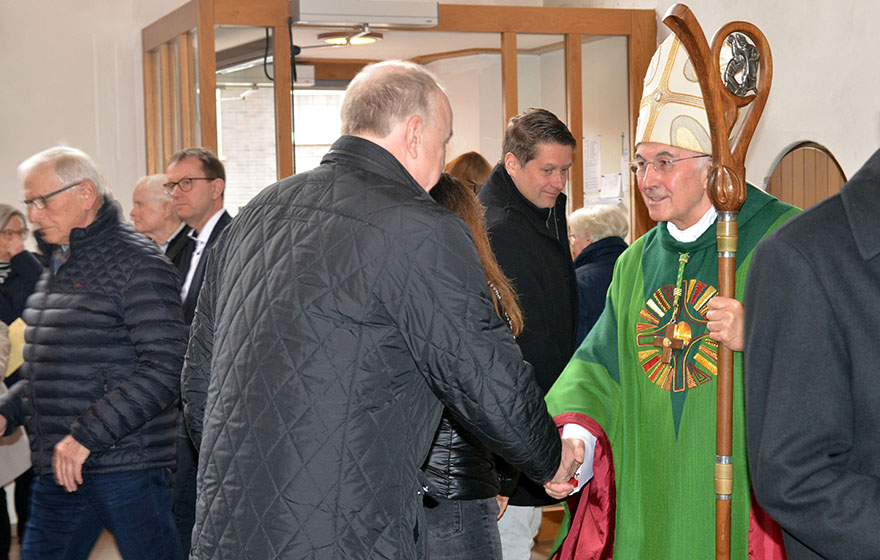 Bischof Genn schüttelt einem Kirchenbesucher die Hand.