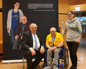 V.l.: Landesarbeitsminister Karl-Josef Laumann und Nicole Deutzkens sitzen bzw. stehen neben dem im Rollstuhl sitzenden Siggi Z. Dahinter steht ein Roll-Up der Ausstellung, das Nicole Deutzkens und Siggi Z. zeigt. V.l.: Landesarbeitsminister Karl-Josef Laumann und Nicole Deutzkens sitzen bzw. stehen neben dem im Rollstuhl sitzenden Siggi Z. Dahinter steht ein Roll-Up der Ausstellung, das Nicole Deutzkens und Siggi Z. zeigt.