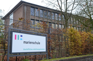 Ein Gebäudeteil de Bischöflichen Mädchengymnasiums Marienschule in Münster. Davor steht ein Schild mit dem Namen der Schule