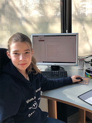 Ein Mädchen sitzt an einem Schreibtisch, auf dem ein aufgeklappter Laptop steht. Ein Mädchen sitzt an einem Schreibtisch, auf dem ein aufgeklappter Laptop steht.