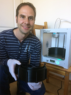 Markus Schnötke kniet vor einem 3-D-Drucker und präsentiert fertige Maskenringe.