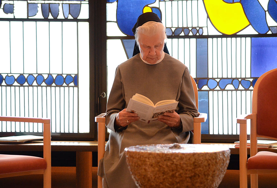 Hinter einem Brunnen stzt eine Ordensfrau und liest ein Buch in der Kapelle.
