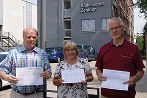 Georg Möllers, Maria Voß und Gustav Peters (von links) stehen nebeneinander und halten Unterschriftenlisten in die Kamera.