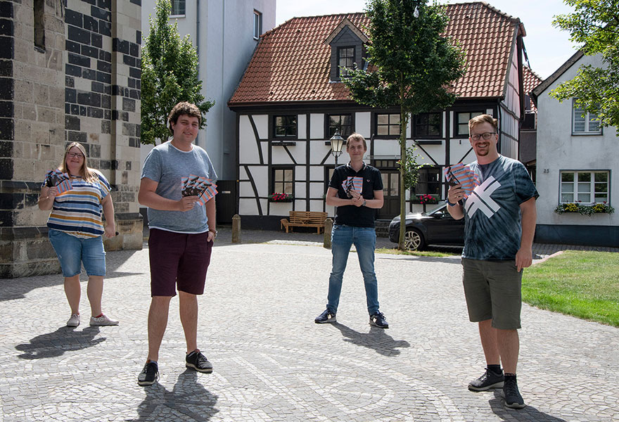 Vanessa Egner, Matthias Weiß, Fabian Christoph und Oliver Berkemeier (von links) stehen auf dem Kirchplatz und halten die Flyer für die Veranstaltungen in der Hand.