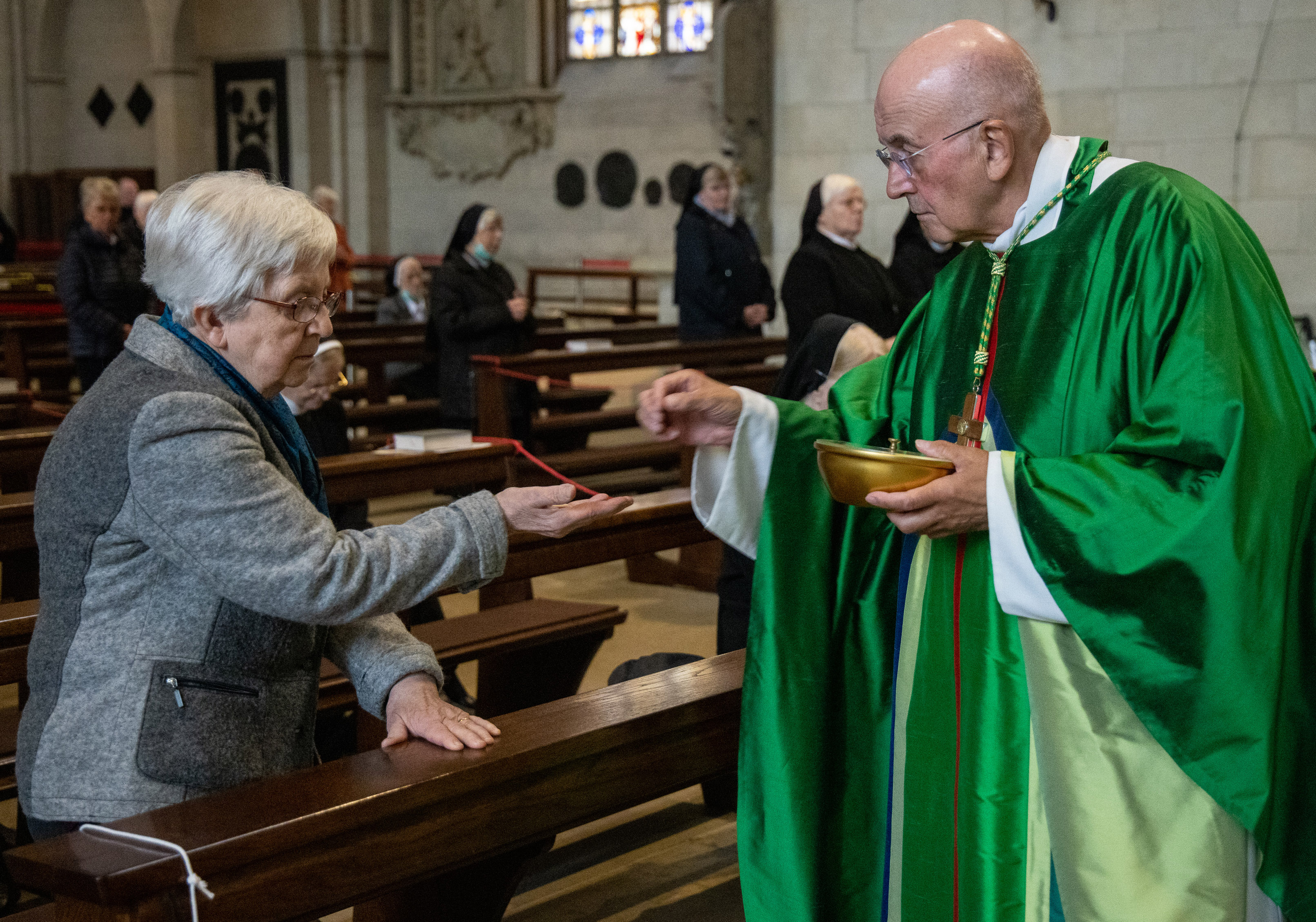 Bischof Felix Genn teilt die Kommunion an eine Ordensfrau aus.