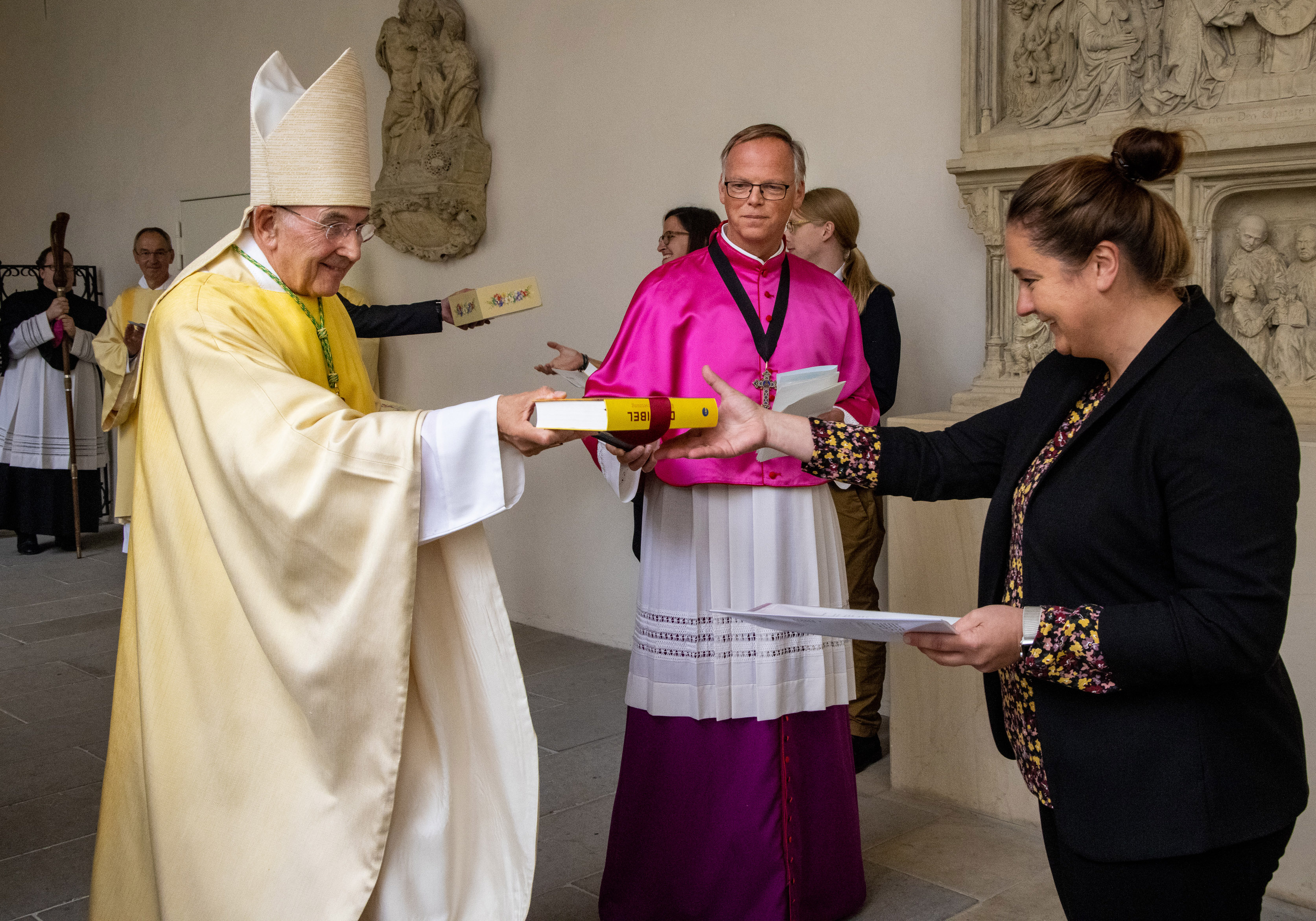 Bischof Felix Genn überreicht einer jungen Frau ein Geschenk. 