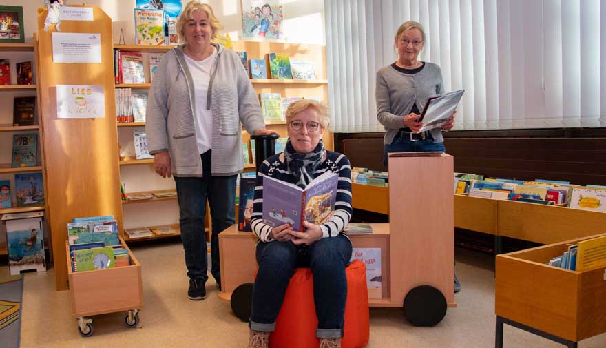 Drei Frauen sind in einer Bücherei.