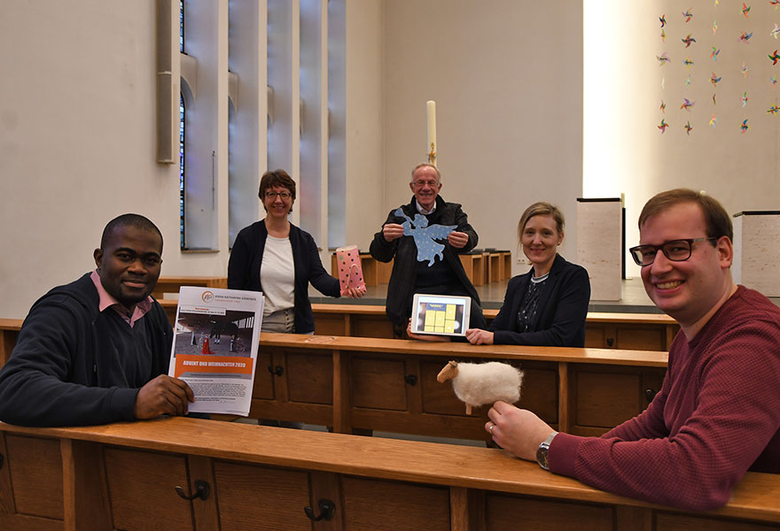 Das Seelsorgeteam sitzt mit Abstand in Kirchenbänken und hält Symbole für die Aktionen in der Hand.