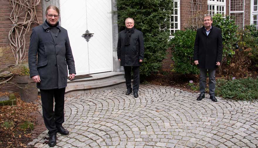 Drei Männer stehen im Atrium des Priesterhauses.