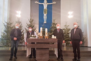 Der Vorsitzende Gustav Peters und sein Stellvertreter Georg Möllers (von rechts) vom Stadtkomitee der Katholiken sowie Marc Gutzeit, Geschäftsführer des Stadtkomitees (links), und Pastor Oliver Paschke stehen am Altar, auf dem die beiden Kerzen zu sehen sind.