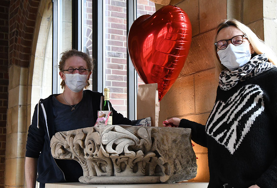 Jane Schulze Scholle und Daniel Gewand stehen mit Masken nebeneinander und haben einen großen Herzluftballon zwischen sich.