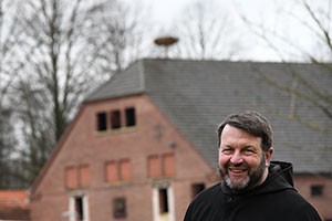 Foto von Pater Kilian. Im Hintergrund sieht man das Nest auf dem Dach.