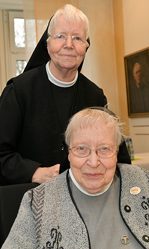 Schwester M. Annefried und seht hinter M. Margrith. Beide lächeln in die Kamera.