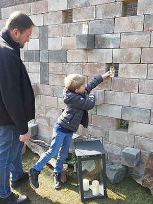 Ein Junge stellt eine Kerze in eine Aussparung der Mauer.