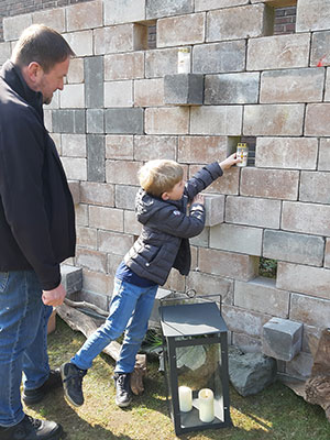 Ein Junge stellt eine Kerze in eine Aussparung der Mauer. Ein Junge stellt eine Kerze in eine Aussparung der Mauer.