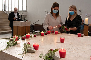 Zwei Frauen entzünden auf dem Altar Kerzen und legen Rosen ab.