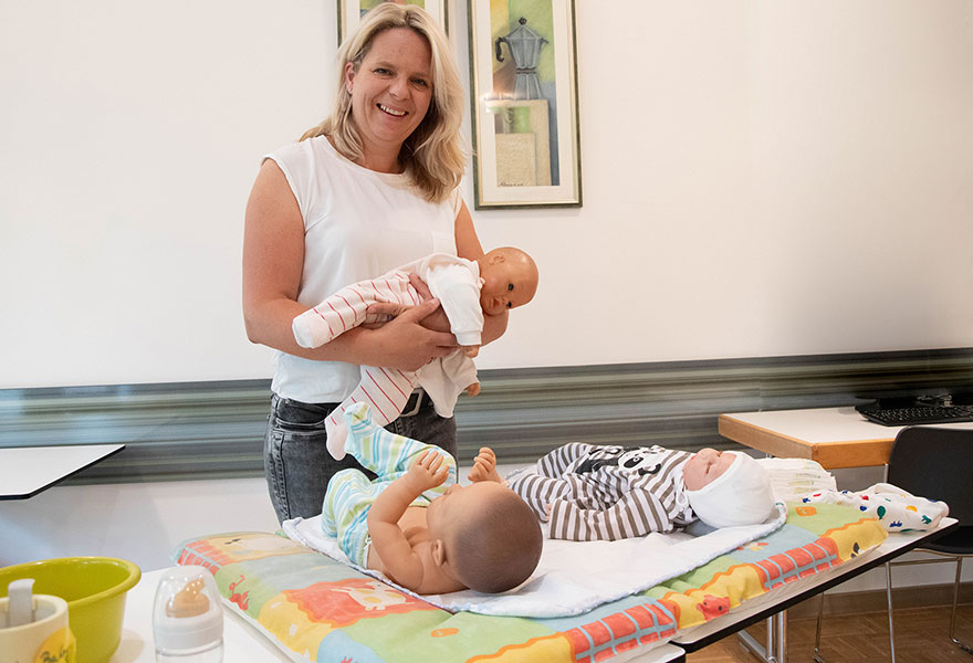 Diana Homoet hat eine Babypuppe auf dem Arm. Vor ihr liegen zwei weitere Puppen.