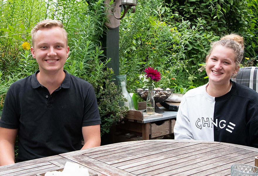 Simon Buttgereit und Johanna Fröhlich sitzen im Garten und lächeln in die Kamera.
