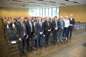 Veranstalter und Referenten stehen nebeneinander vor den gefüllten Zuschauerreihen. Veranstalter und Referenten stehen nebeneinander vor den gefüllten Zuschauerreihen.