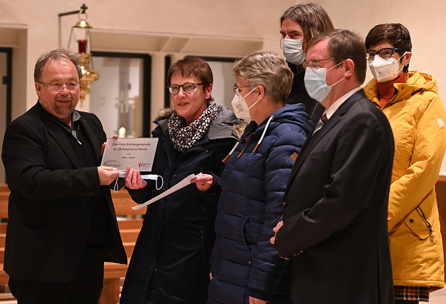 Thomas Kamp-Deister überreicht einer Gruppe ein Schild.