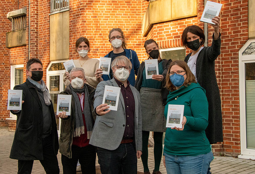 Die Beteiligten haben sich zum Gruppenbild aufgestellt und halten das Buch in der Hand.