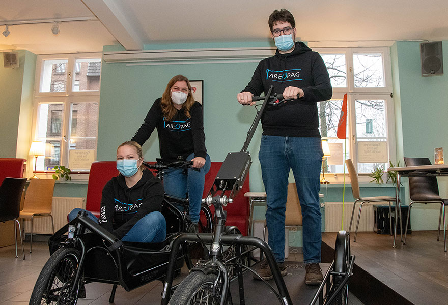 Fiona Bogatzki hat sich in das Lastenrad und Franziska Großheger auf das Lastenrad gesetzt, Matthias Grammann steht daneben in dem neuen Anhänger.