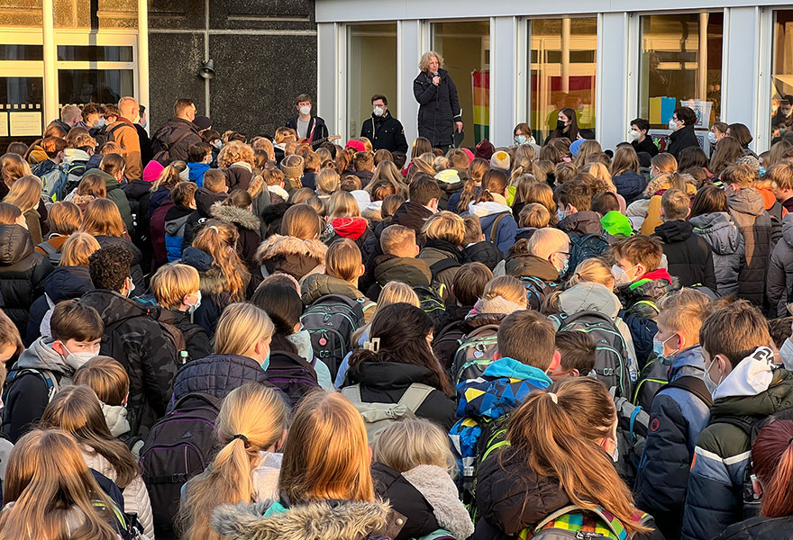 Viele Schülerinnen und Schüler sind zu sehen, die der Schulseelsorgerin zuhören.