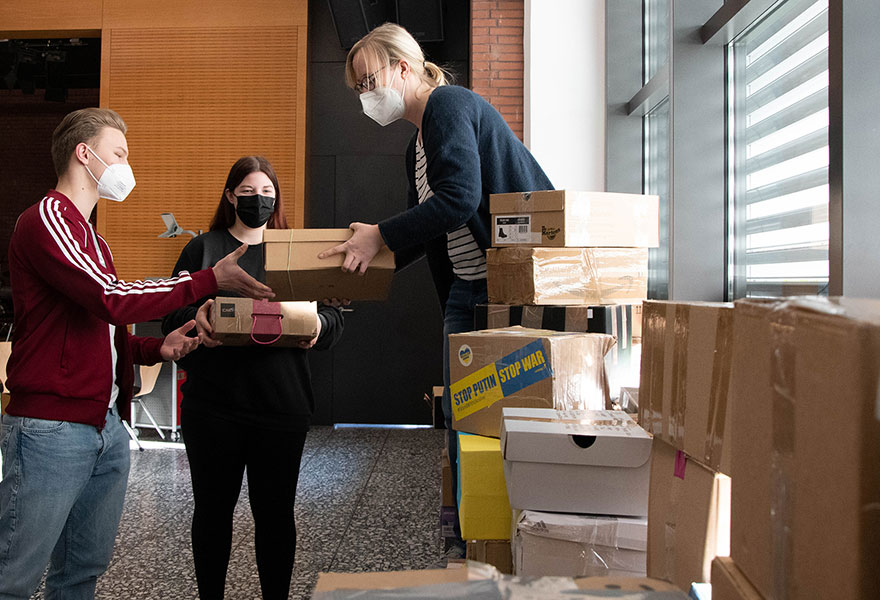 Janis Leska und Chiara Autermann reichen Barbara Kockmann Pakete an.