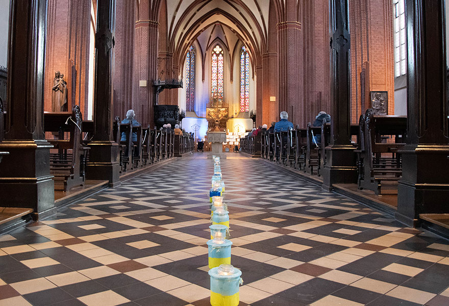 Blau-gelbe Windlichter stehen im Mittelgang der Kirche.