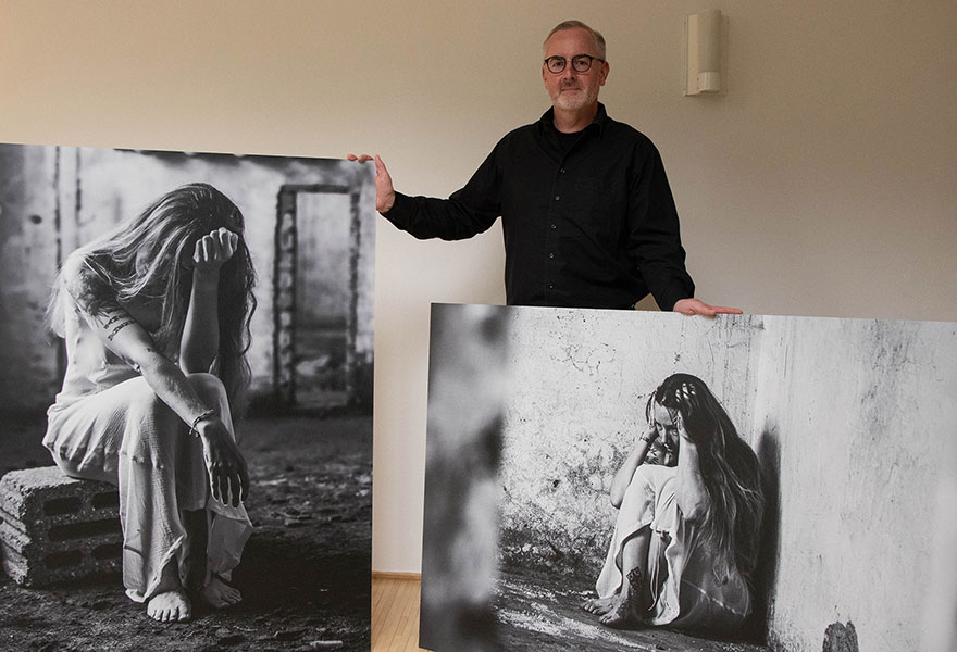Ulrich Richartz steht zwischen zwei großen Fotos.
