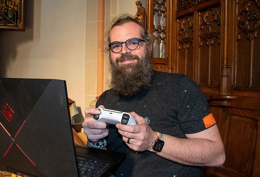 Pfarrer Rother ist mit einem Laptop und einem Controller im Chorgestühl.