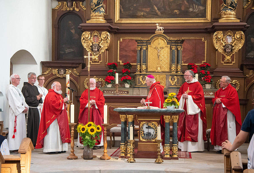 Im Altarraum der Kirche stehen die Kapuziner und der Bischof in roten Gewändern. Im Altarraum der Kirche stehen die Kapuziner und der Bischof in roten Gewändern.
