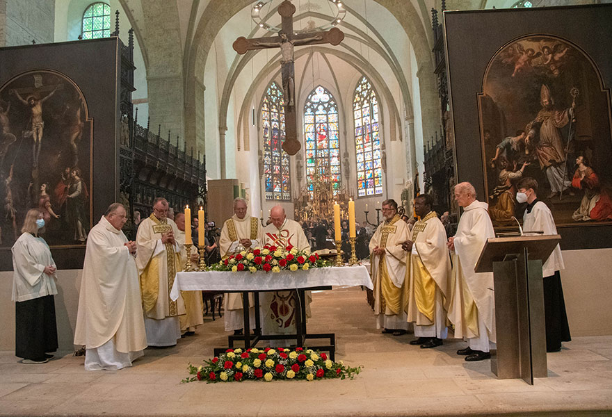 Die Priester stehen um den geschmückten Altar herum.