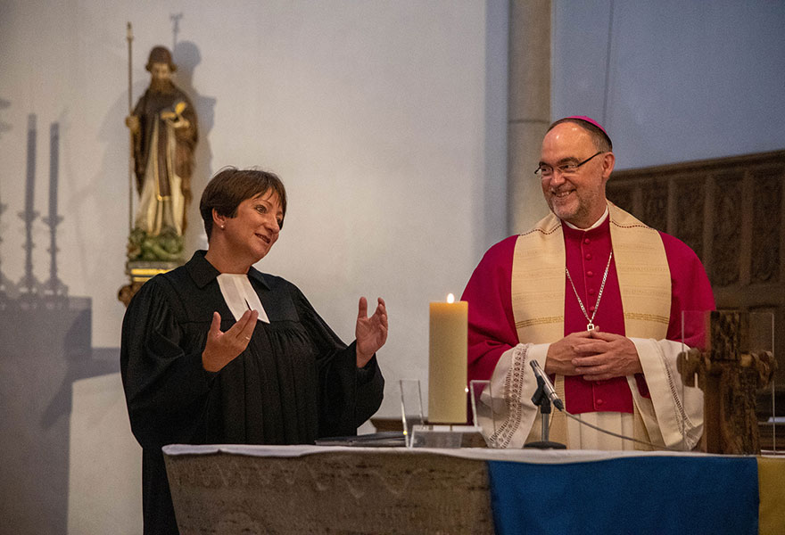 Superintendentin und Weihbischof stehen am Altar.